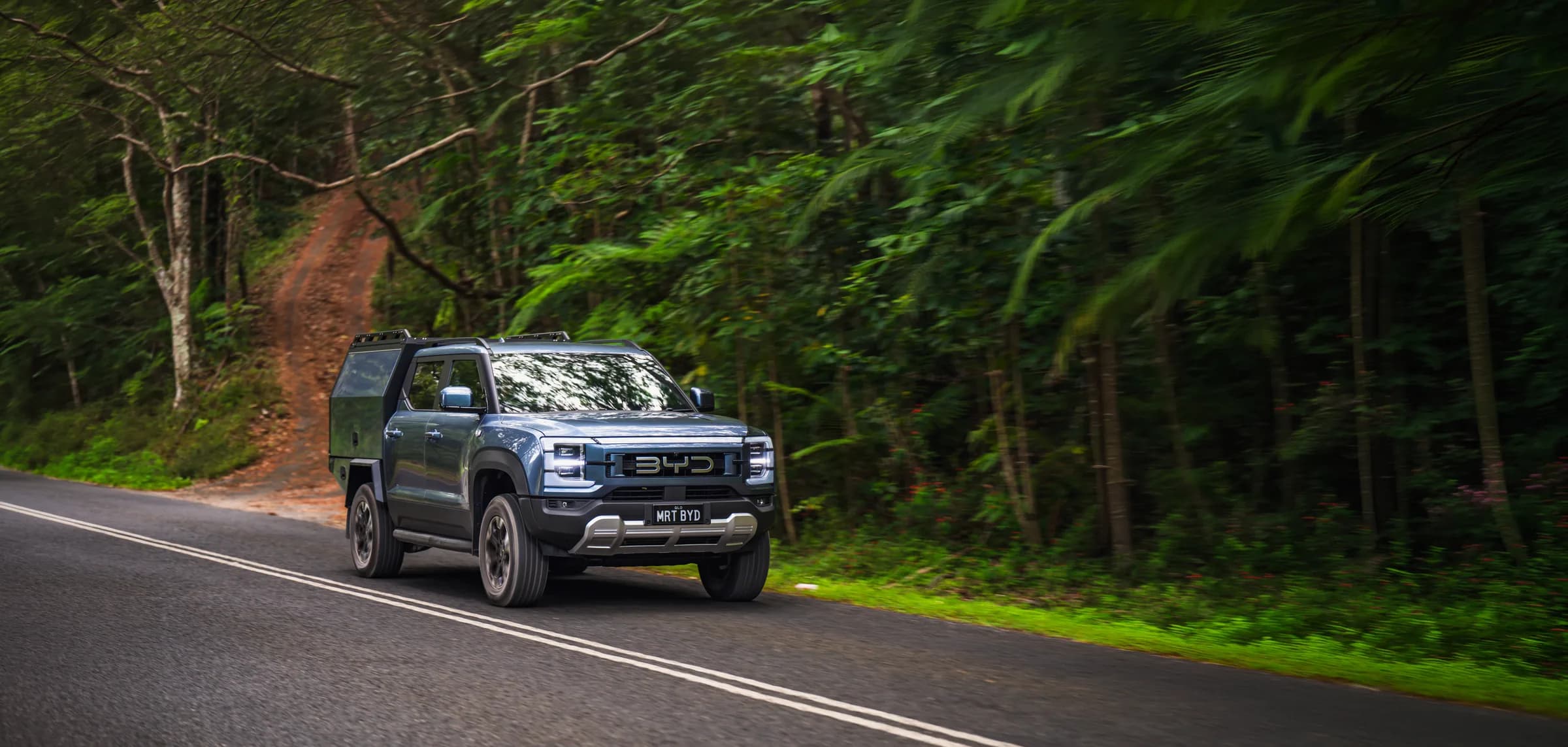 BYD Shark ute with MRT canopy driving on a forest road