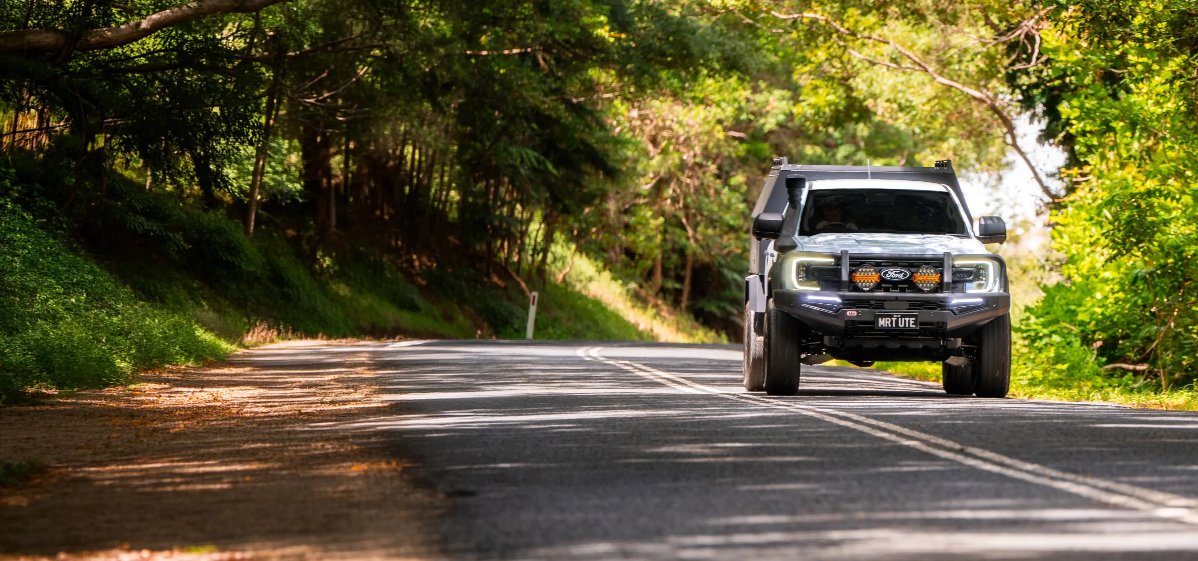Ford Ranger fitted with a certified MRT Ford Pro™ Convertor canopy build, driving on a tree-lined Australian country road